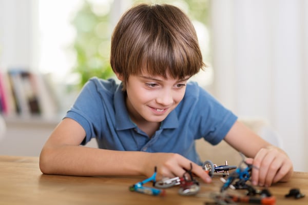 Young boy playing with a toy helicopter at home smiling a he constructs the model in an educational fun concept